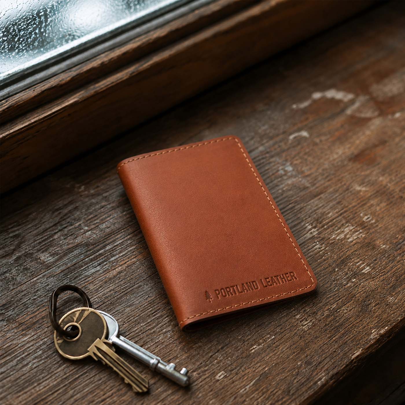 Toscano | A leather card holder resting on a rustic wooden table next to a set of keys