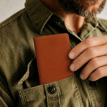 Toscano | A close-up of a model sliding a leather card holder into their shirt pocket