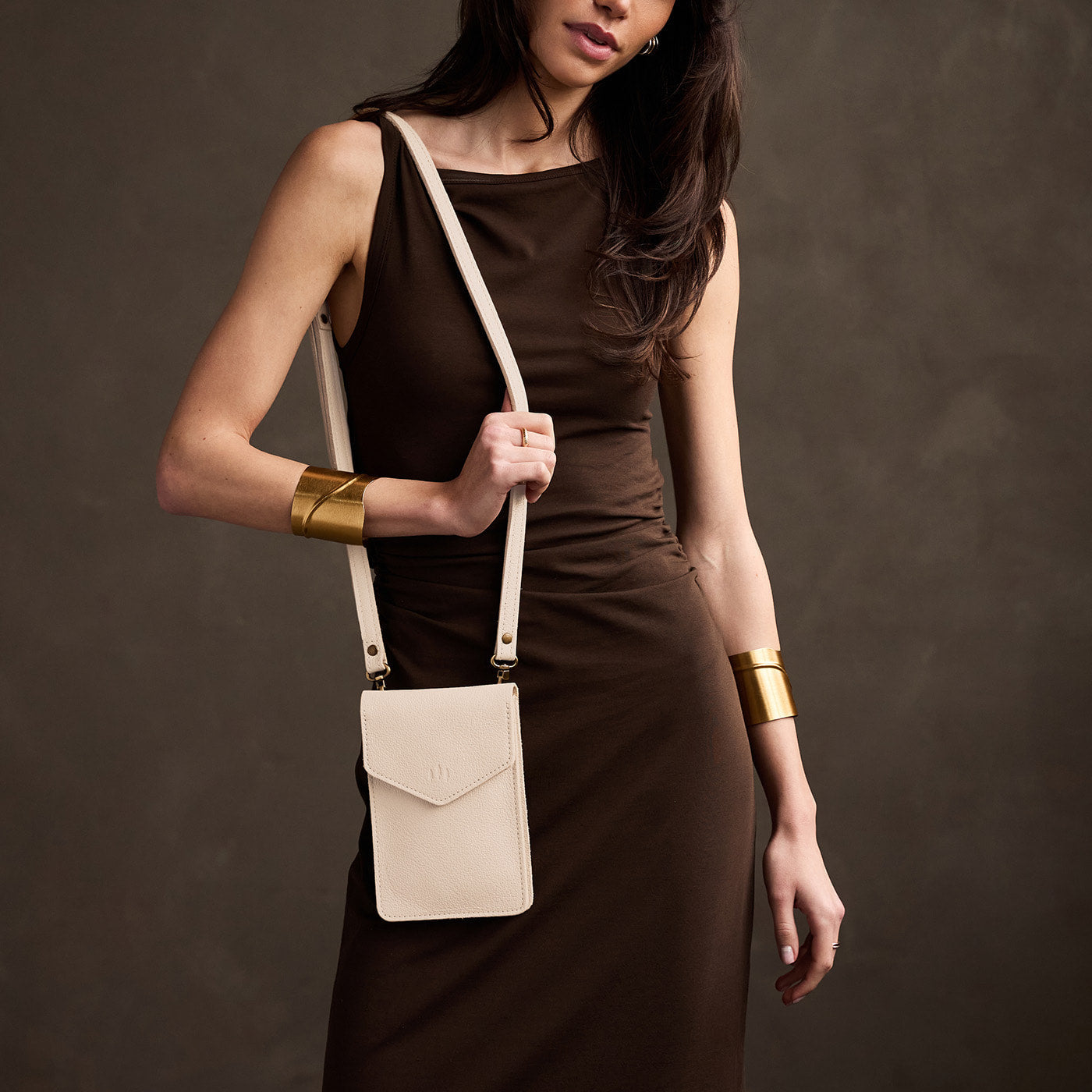 Pebbled Bone | Model wearing slim, phone-shaped crossbody purse with magnetic closure