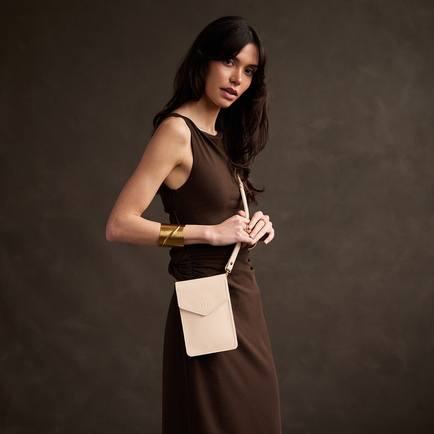 Pebbled Bone | Model wearing slim, phone-shaped crossbody purse with magnetic closure