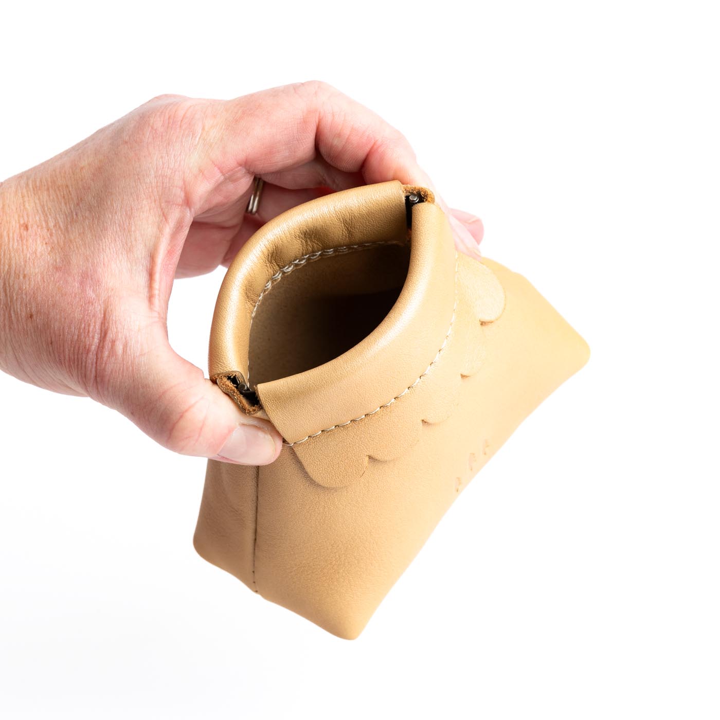 Champagne | Hand holding leather coin pouch with scalloped edge and three Portland leather tree emblems open
