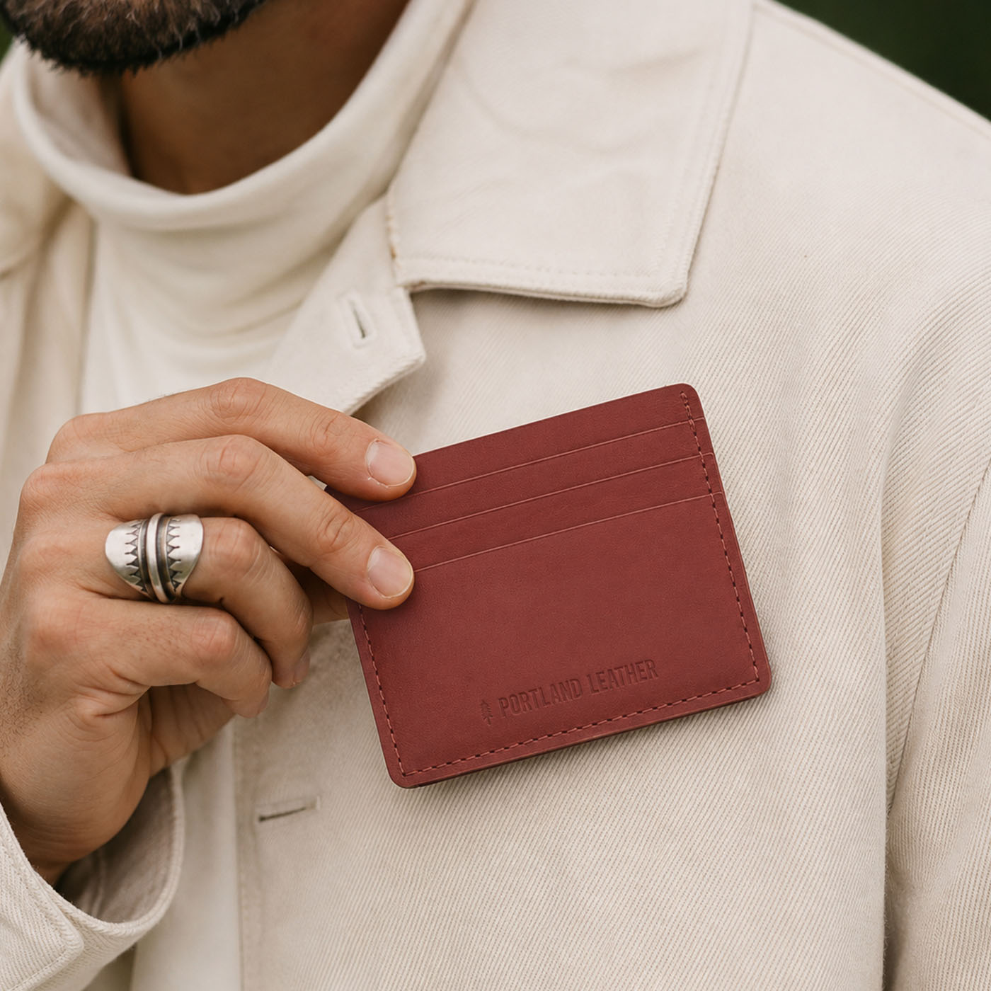 Marrone | A close-up lifestyle shot of a model holding a leather card holder