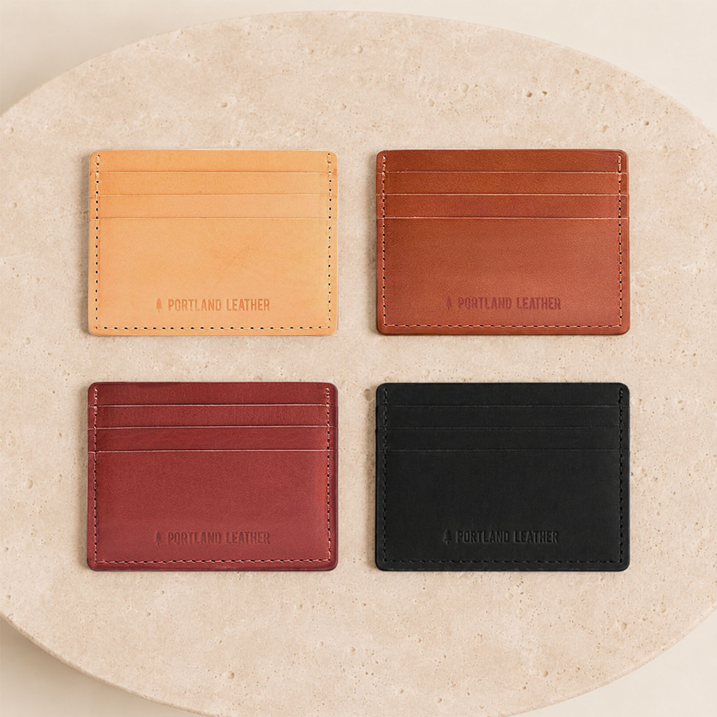 Naturale | Group of wallets arranged in a 2x2 grid on a round beige stone slab