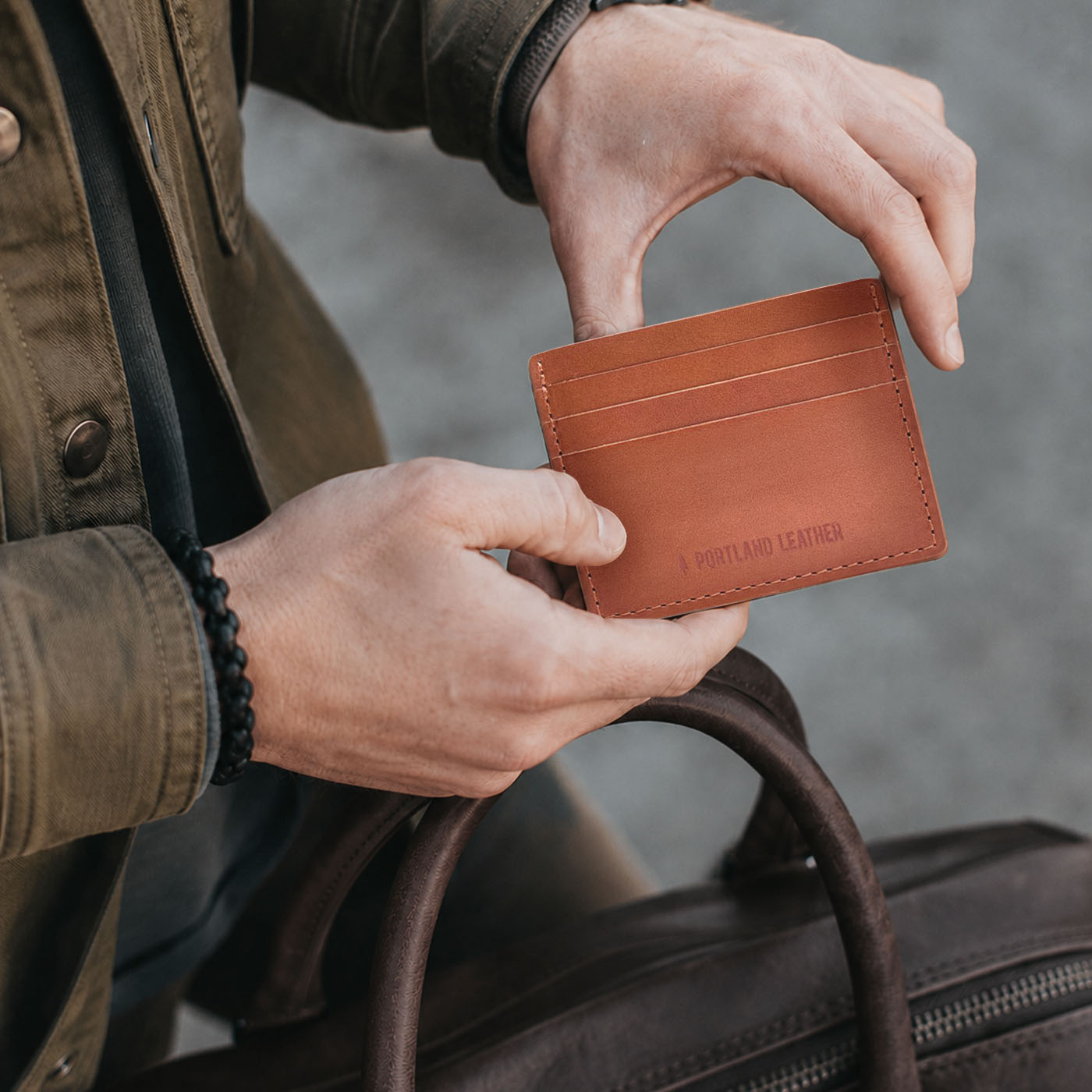 Toscano | A close-up lifestyle shot of a model holding a leather card holder