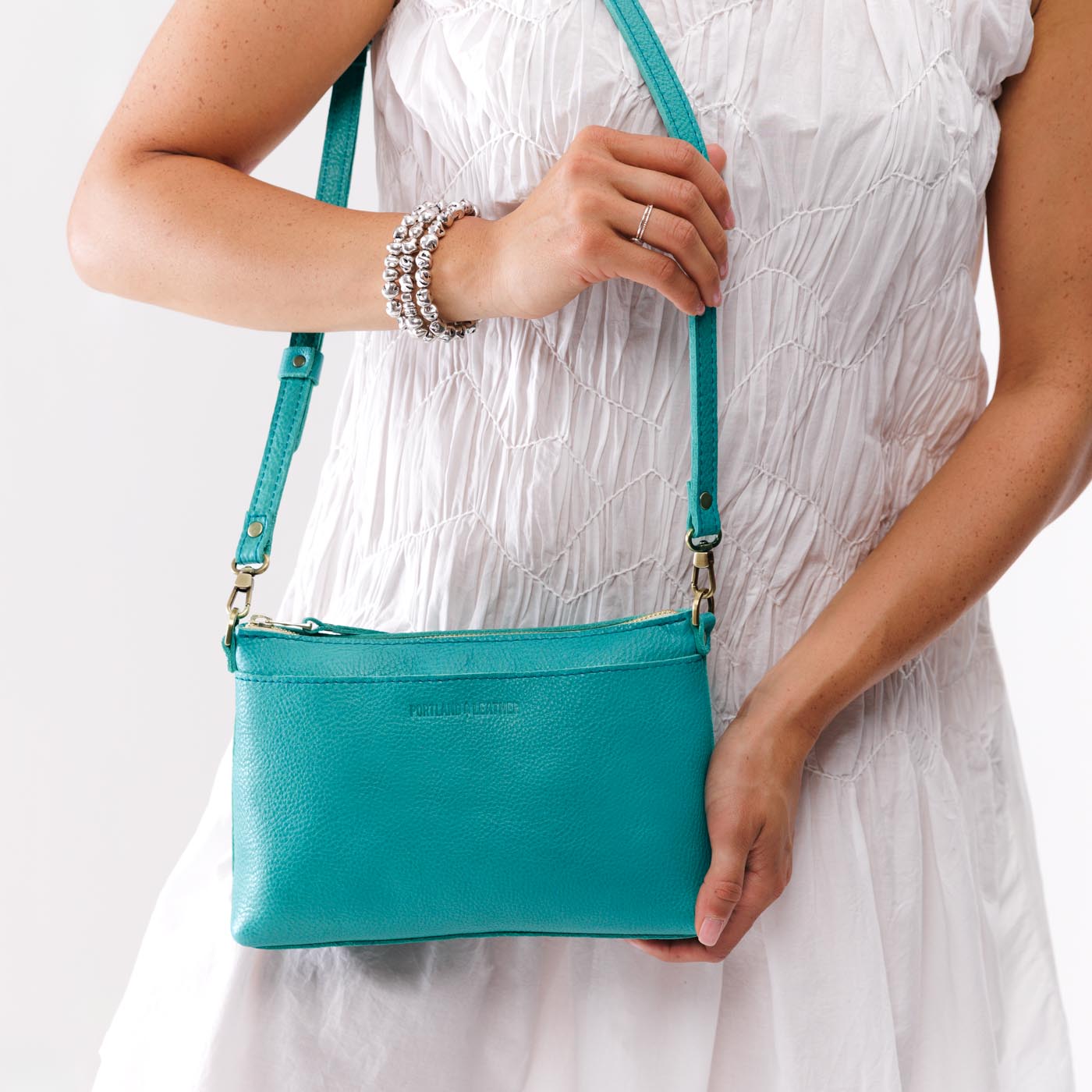 Seafoam*Small | Model holding a zip top crossbody bag with detachable strap