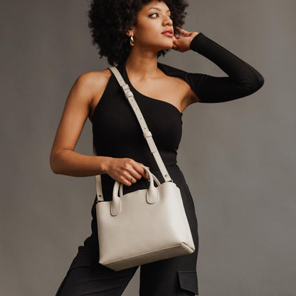Bone*Large | Model holding mid-size tote purse with structured leather handles and crossbody strap