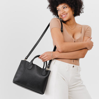 Pebbled--black*Large | Model holding mid-size tote purse with structured leather handles and crossbody strap