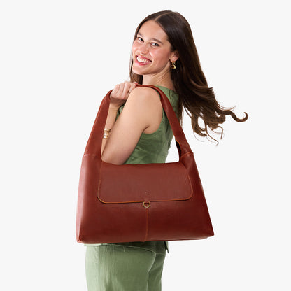 Nutmeg*Large | A model holding a slouchy triangle shaped shoulder bag with a flap