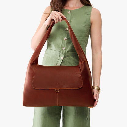 Nutmeg*Large | A model holding a slouchy triangle shaped shoulder bag with a flap