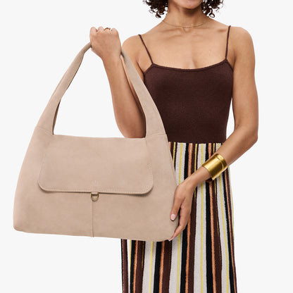 Taupe*Large | A model holding a slouchy triangle shaped shoulder bag with a flap