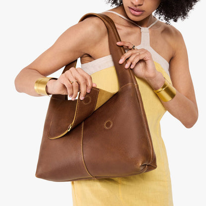 Asheville*Medium | A model holding a slouchy triangle shaped shoulder bag with a flap