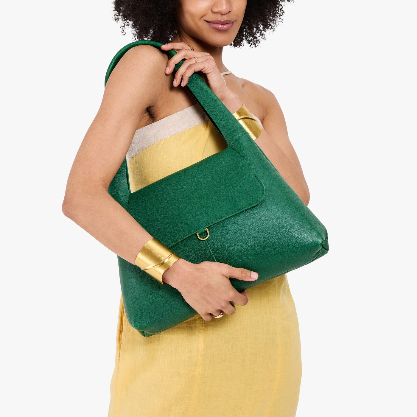 Bacalar*Medium | A model holding a slouchy triangle shaped shoulder bag with a flap