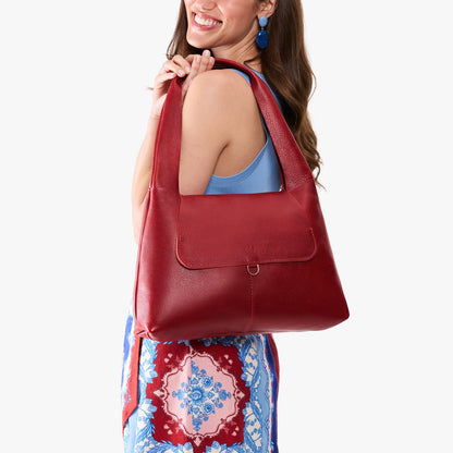 Chili Red*Medium | A model holding a slouchy triangle shaped shoulder bag with a flap