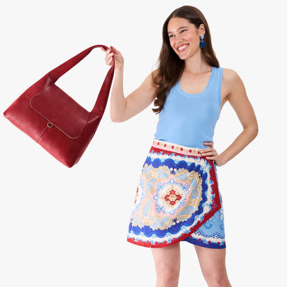Chili Red*Medium | A model holding a slouchy triangle shaped shoulder bag with a flap