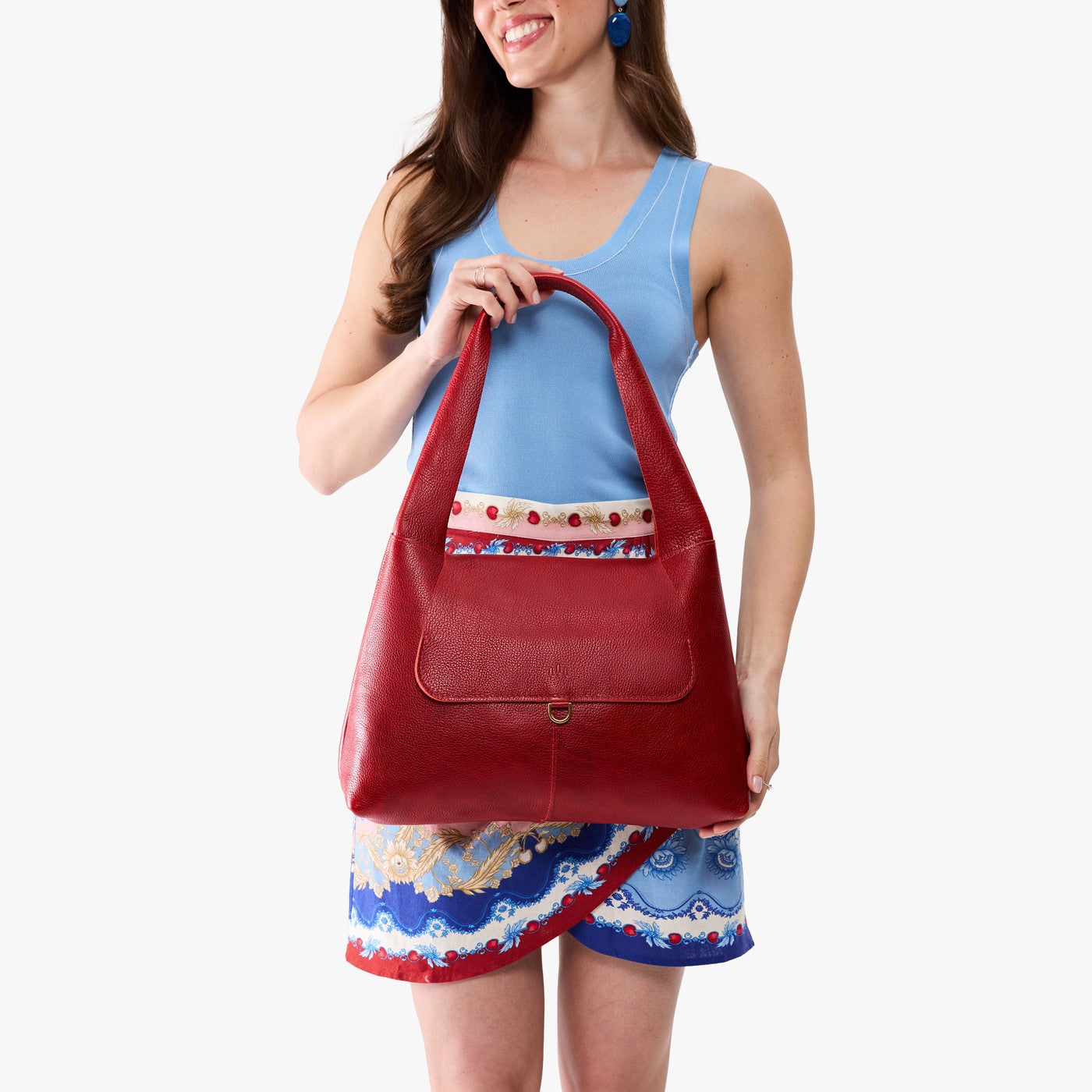 Chili Red*Medium | A model holding a slouchy triangle shaped shoulder bag with a flap