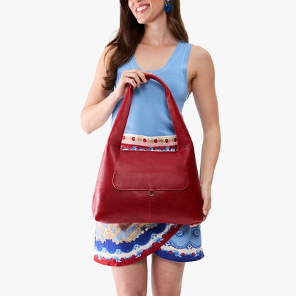 Chili Red*Medium | A model holding a slouchy triangle shaped shoulder bag with a flap