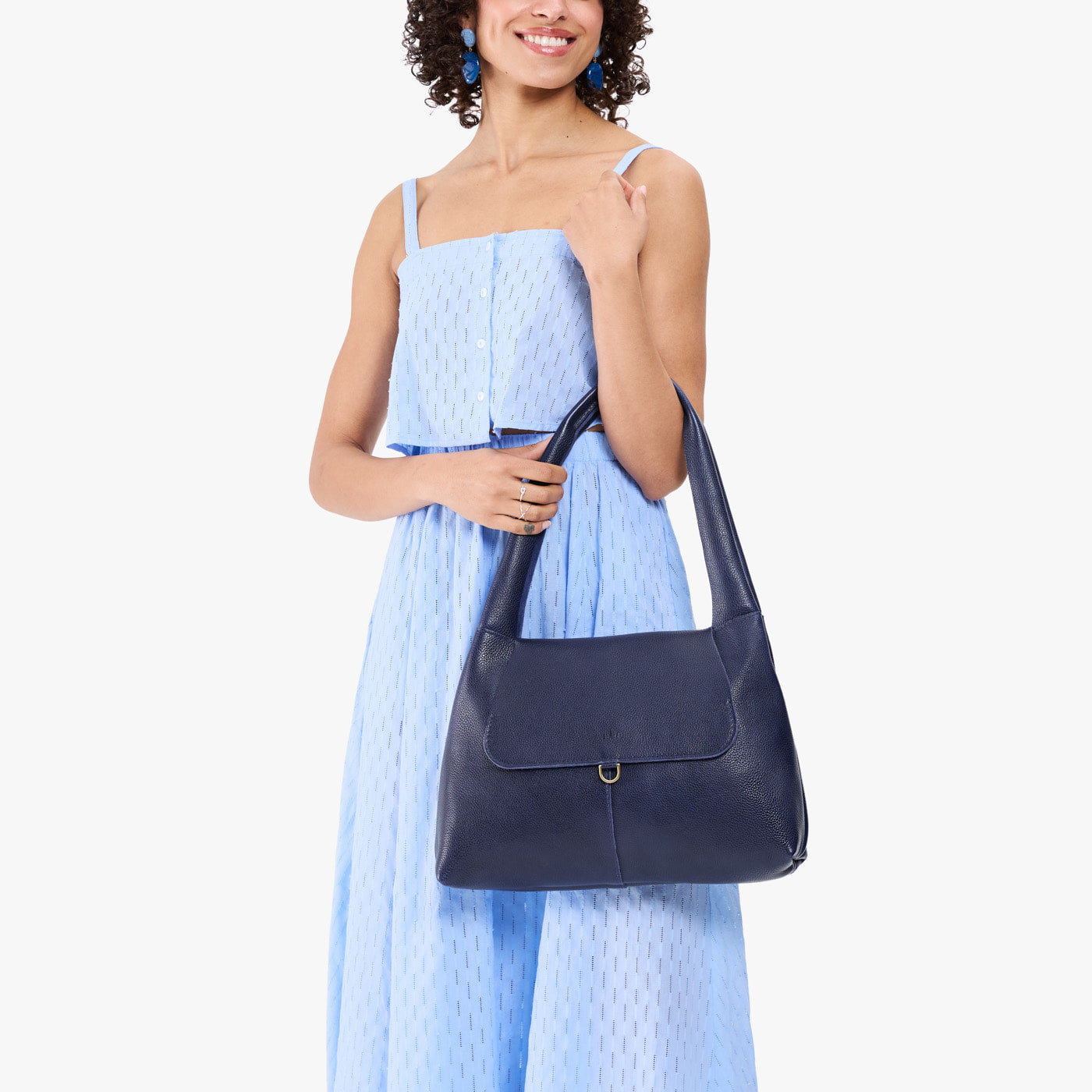 Cobalt*Medium | A model holding a slouchy triangle shaped shoulder bag with a flap