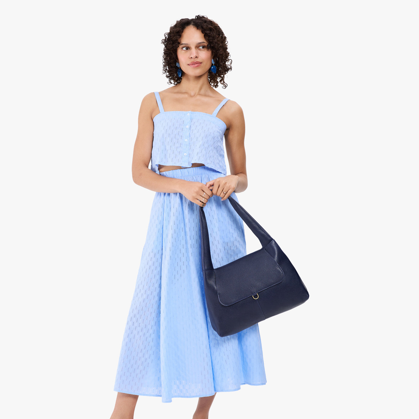 Cobalt*Medium | A model holding a slouchy triangle shaped shoulder bag with a flap