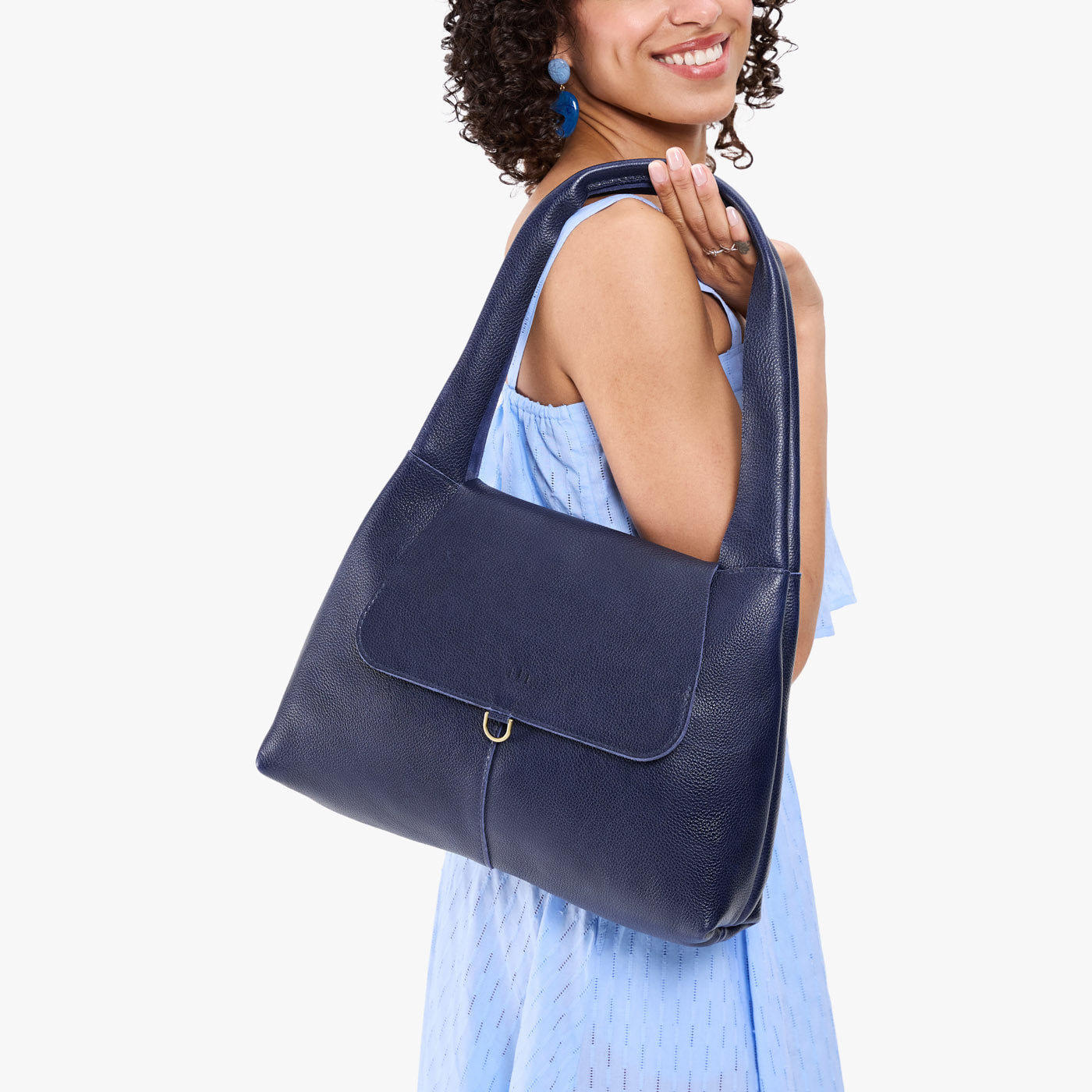 Cobalt*Medium | A model holding a slouchy triangle shaped shoulder bag with a flap