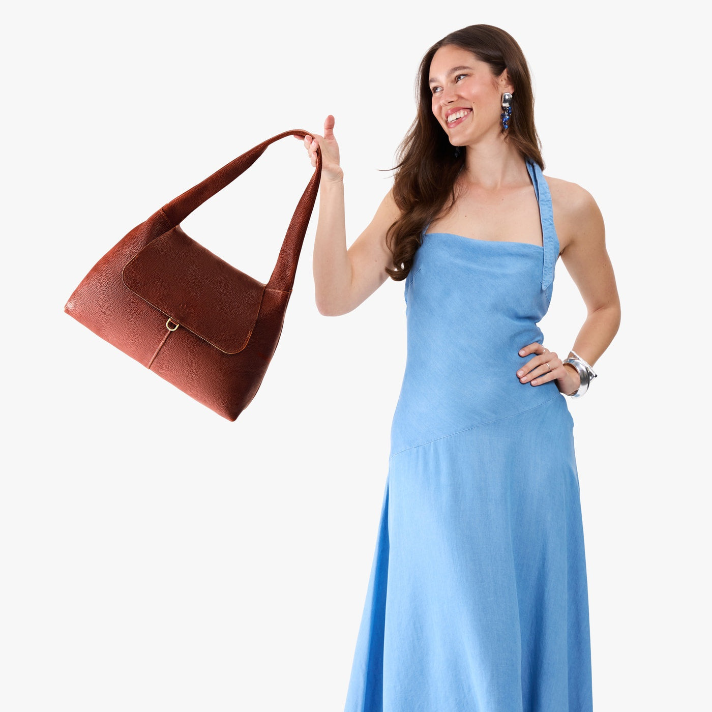 Nutmeg*Medium | A model holding a slouchy triangle shaped shoulder bag with a flap