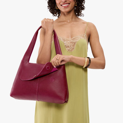 Orchid*Medium | A model holding a slouchy triangle shaped shoulder bag with a flap