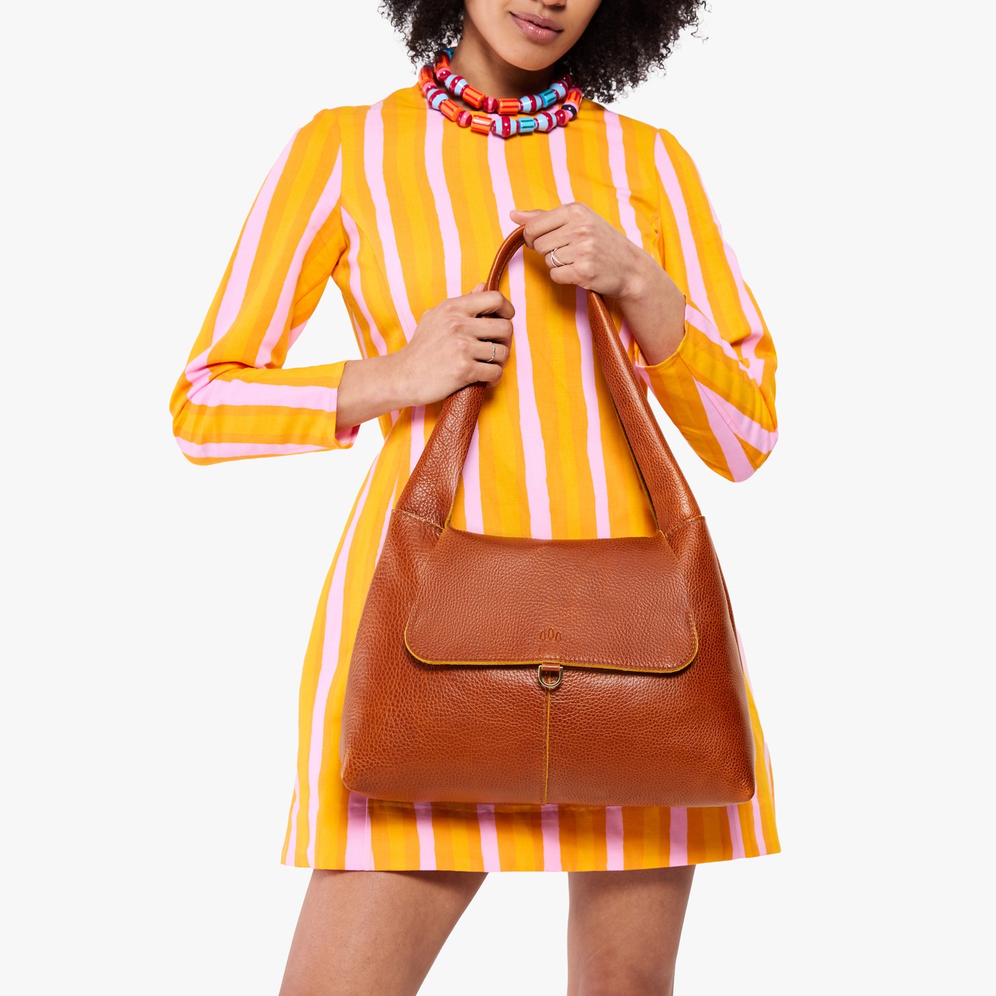 Sienna*Medium | A model holding a slouchy triangle shaped shoulder bag with a flap