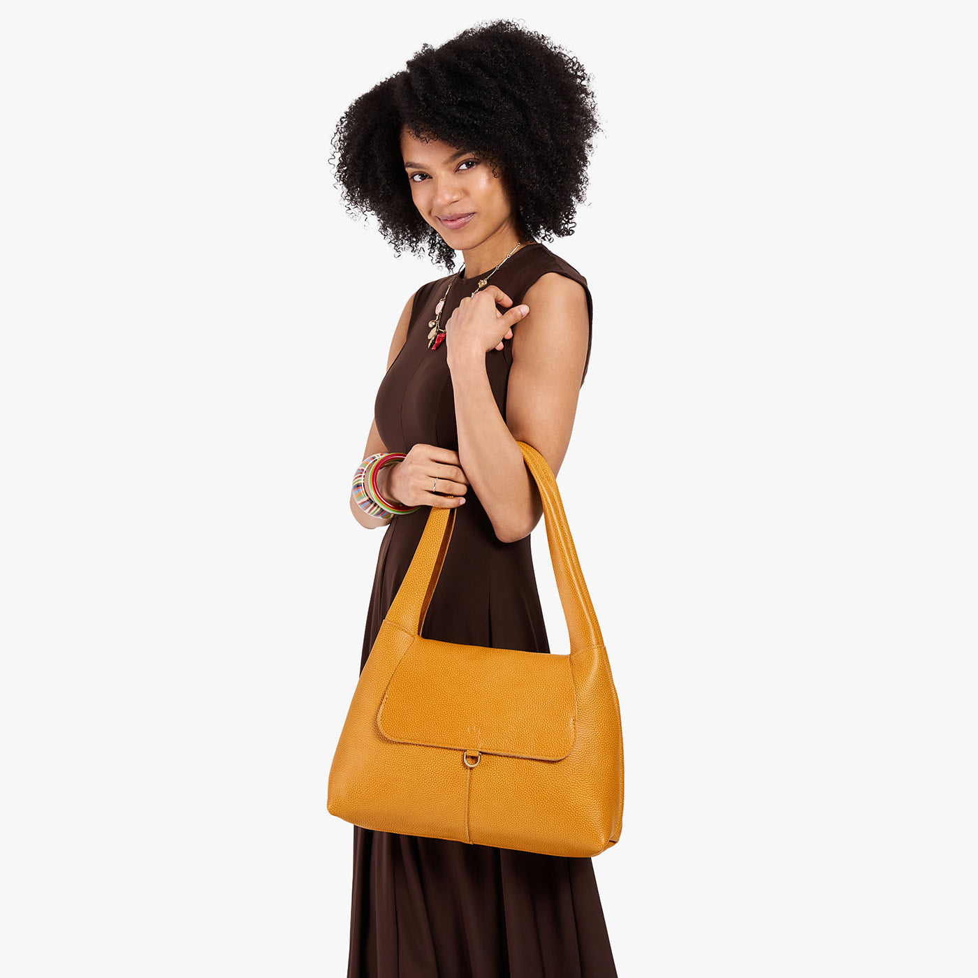 Sunshine*Medium | A model holding a slouchy triangle shaped shoulder bag with a flap