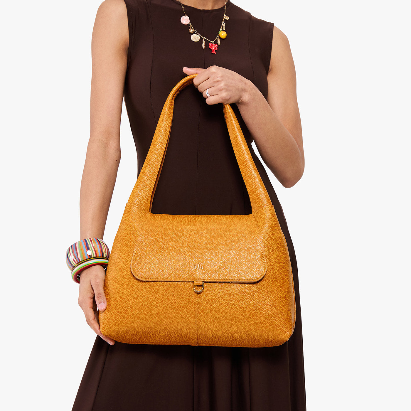 Sunshine*Medium | A model holding a slouchy triangle shaped shoulder bag with a flap