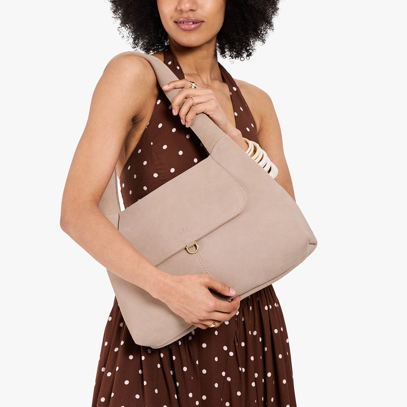 Taupe*Medium | A model holding a slouchy triangle shaped shoulder bag with a flap