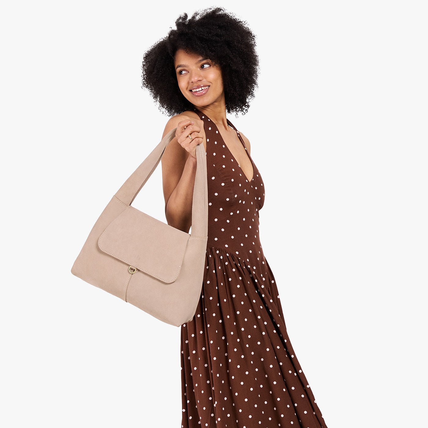 Taupe*Medium | A model holding a slouchy triangle shaped shoulder bag with a flap