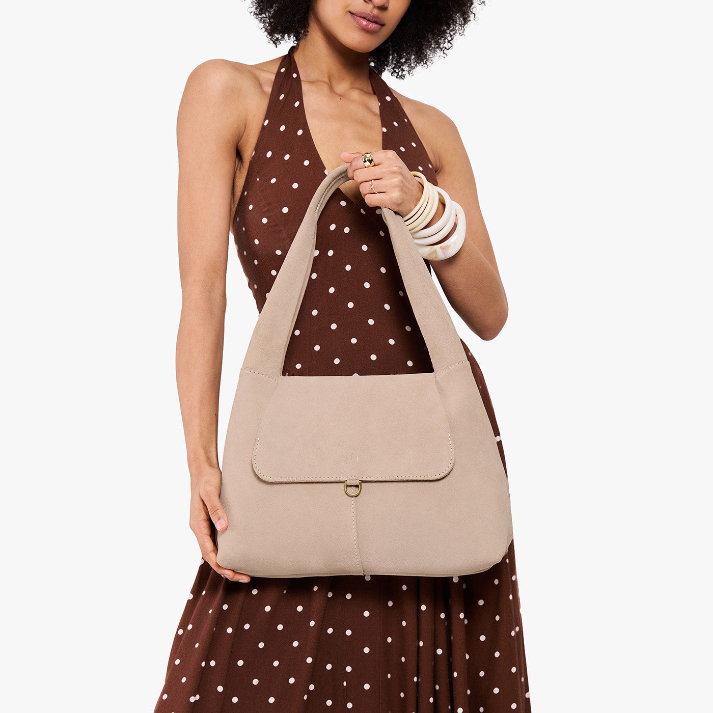 Taupe*Medium | A model holding a slouchy triangle shaped shoulder bag with a flap