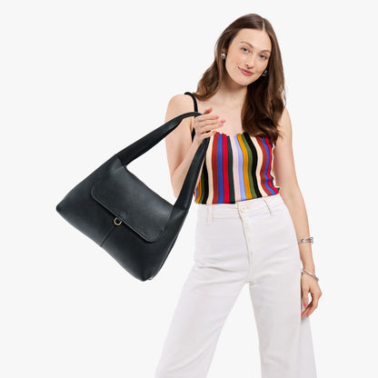 Pebbled--black*Medium | A model holding a slouchy triangle shaped shoulder bag with a flap