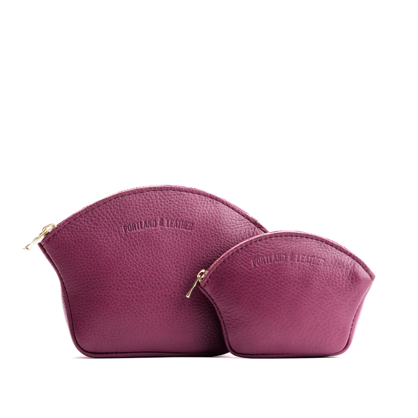 Iris | Comparison shot of small and large seashell shaped leather makeup bags with curved top zipper and flat bottom