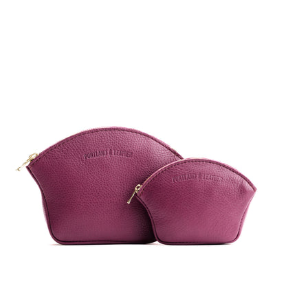 Iris | Comparison shot of small and large seashell shaped leather makeup bags with curved top zipper and flat bottom