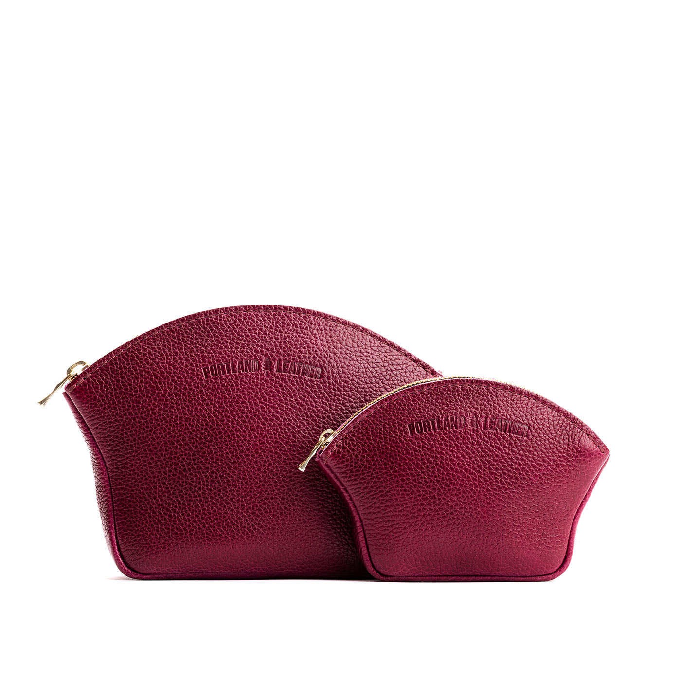 Orchid | Comparison shot of small and large seashell shaped leather makeup bags with curved top zipper and flat bottom