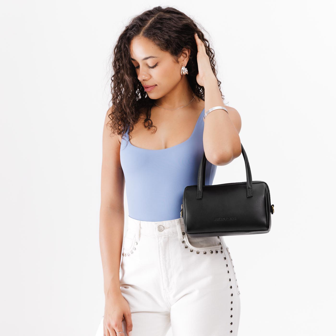 Black*Small | Model wearing mini duffle shaped handbag with crossbody strap