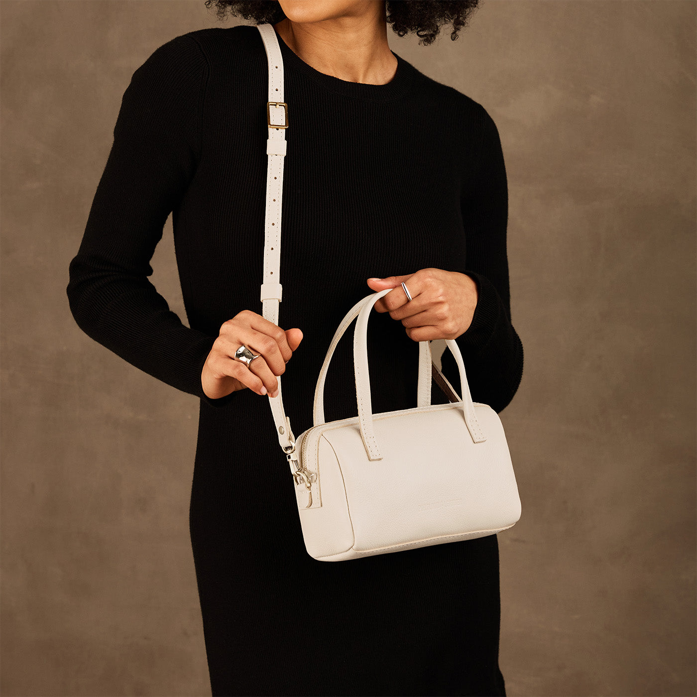 Pebbled Bone*Small | Model holding mini duffle shaped handbag with crossbody strap