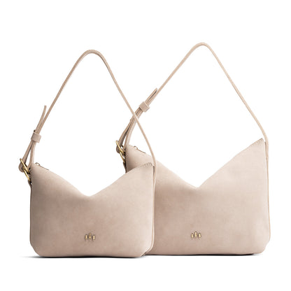 Taupe | Size comparison shot of small and large slouchy shoulder bags with zipper opening and three metal tree emblems
