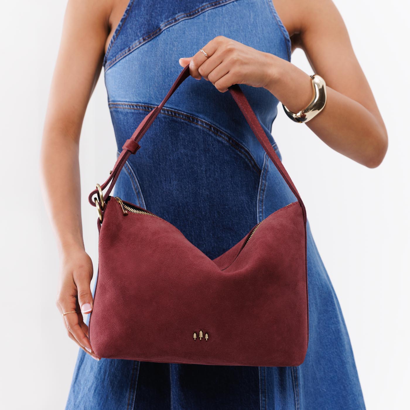 Red Panda*Large | Model holding medium sized slouchy leather shoulder bag with zipper opening and three metal tree emblems