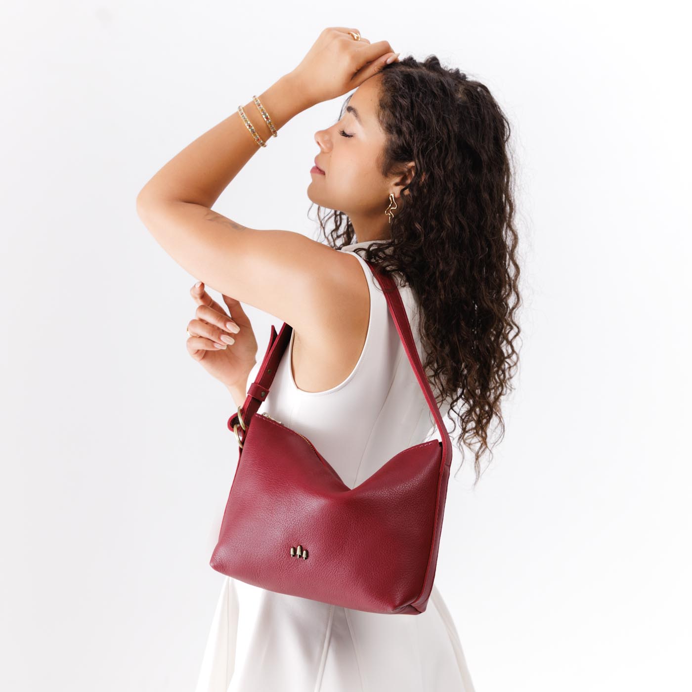Flamenco*Small | Model wearing petite slouchy leather shoulder bag with zipper opening and three metal tree emblems