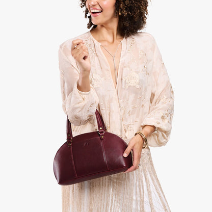 Cabernet*Small | Model holding a half circle crossbody bag with handles and removable crossbody strap