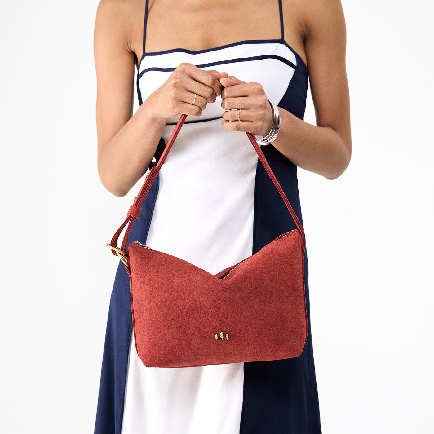 Cinnabar*Small | Model holding a Slouchy Shoulder Bag that has a zipper opening and three metal tree emblems