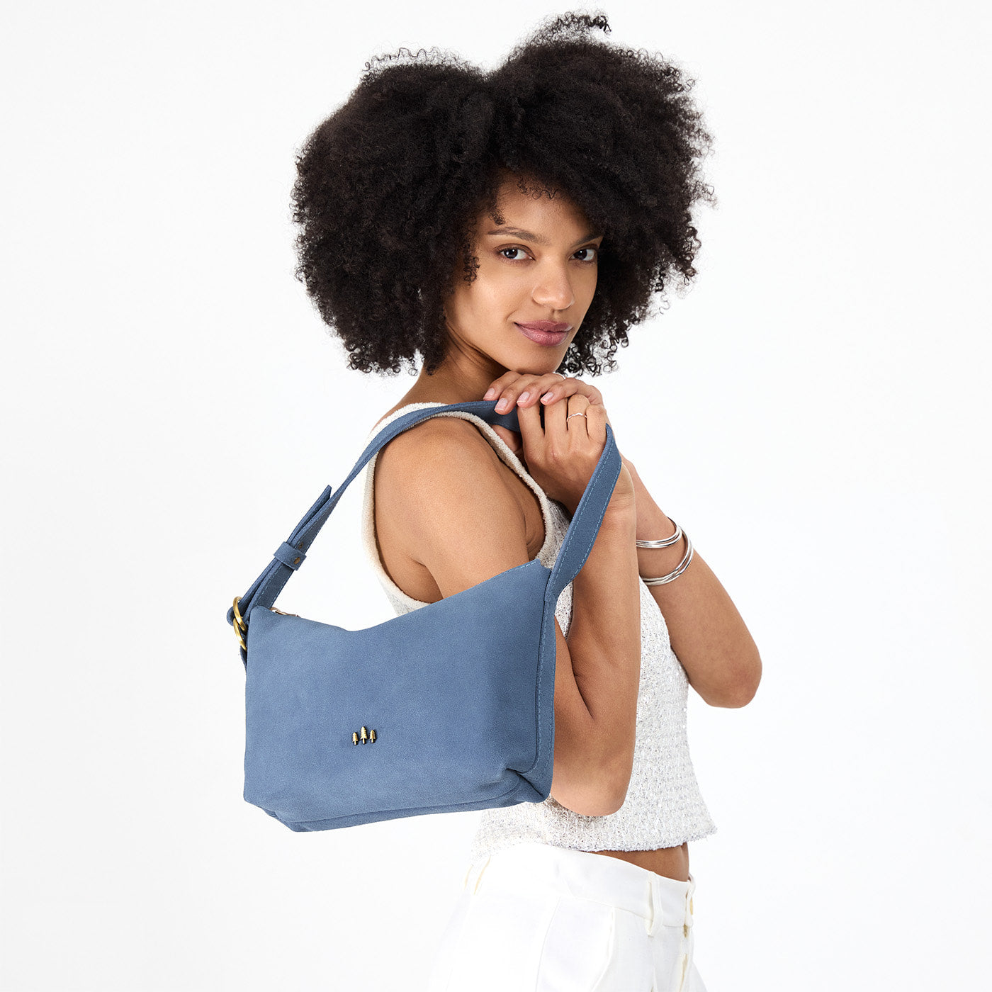 Denim*Small | Model holding a Slouchy Shoulder Bag that has a zipper opening and three metal tree emblems