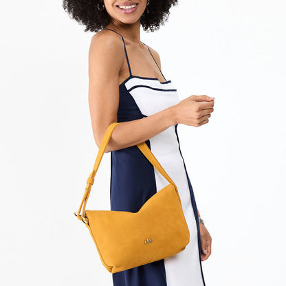 Dijon*Small | Model holding a Slouchy Shoulder Bag that has a zipper opening and three metal tree emblems