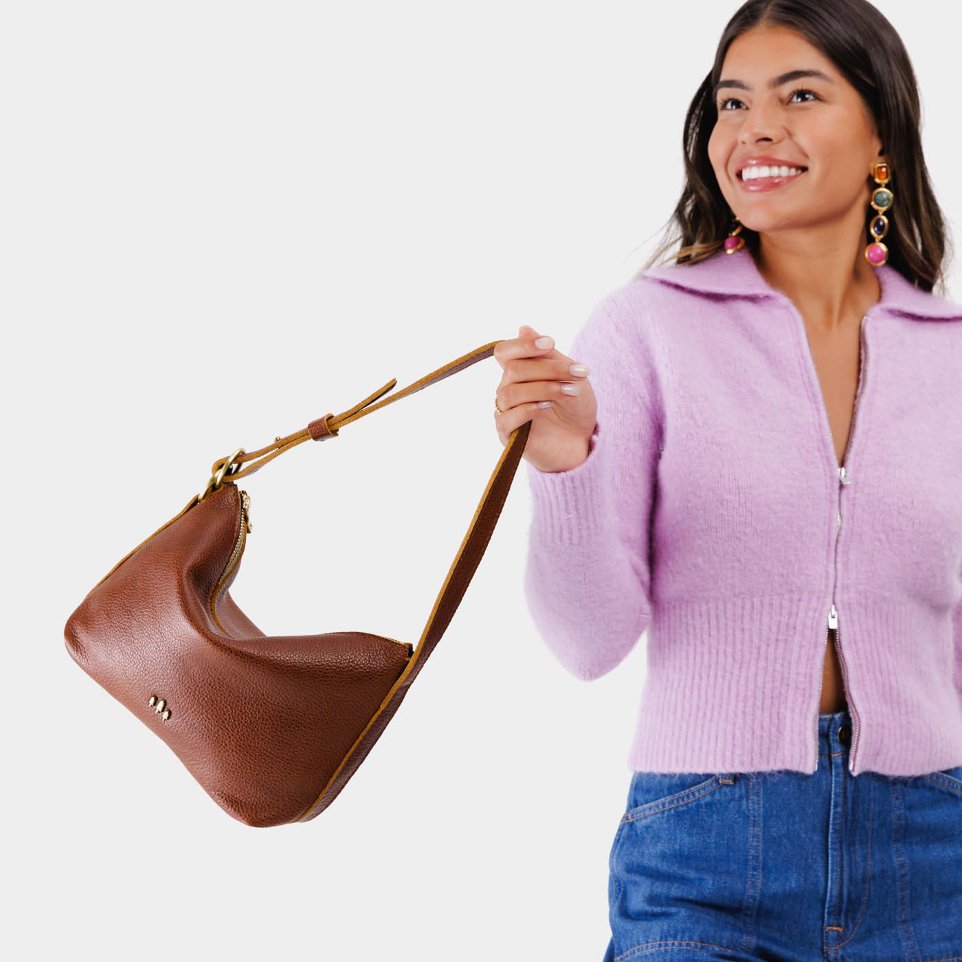 Nutmeg*Small | Model holding petite slouchy leather shoulder bag with zipper opening and three metal tree emblems