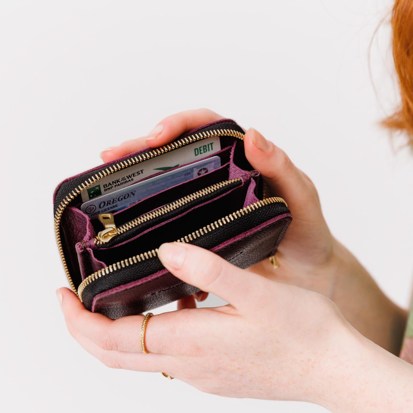Plum | Model holding small leather wallet with zipper open