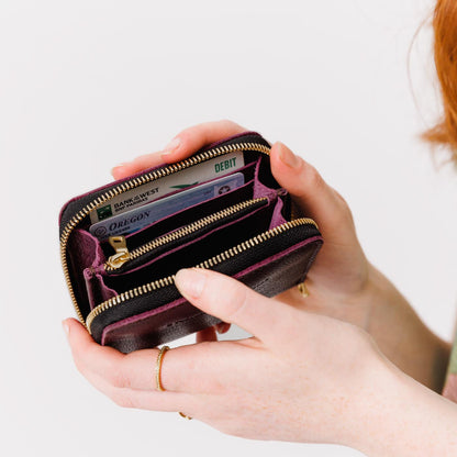 Plum | Model holding small leather wallet with zipper open