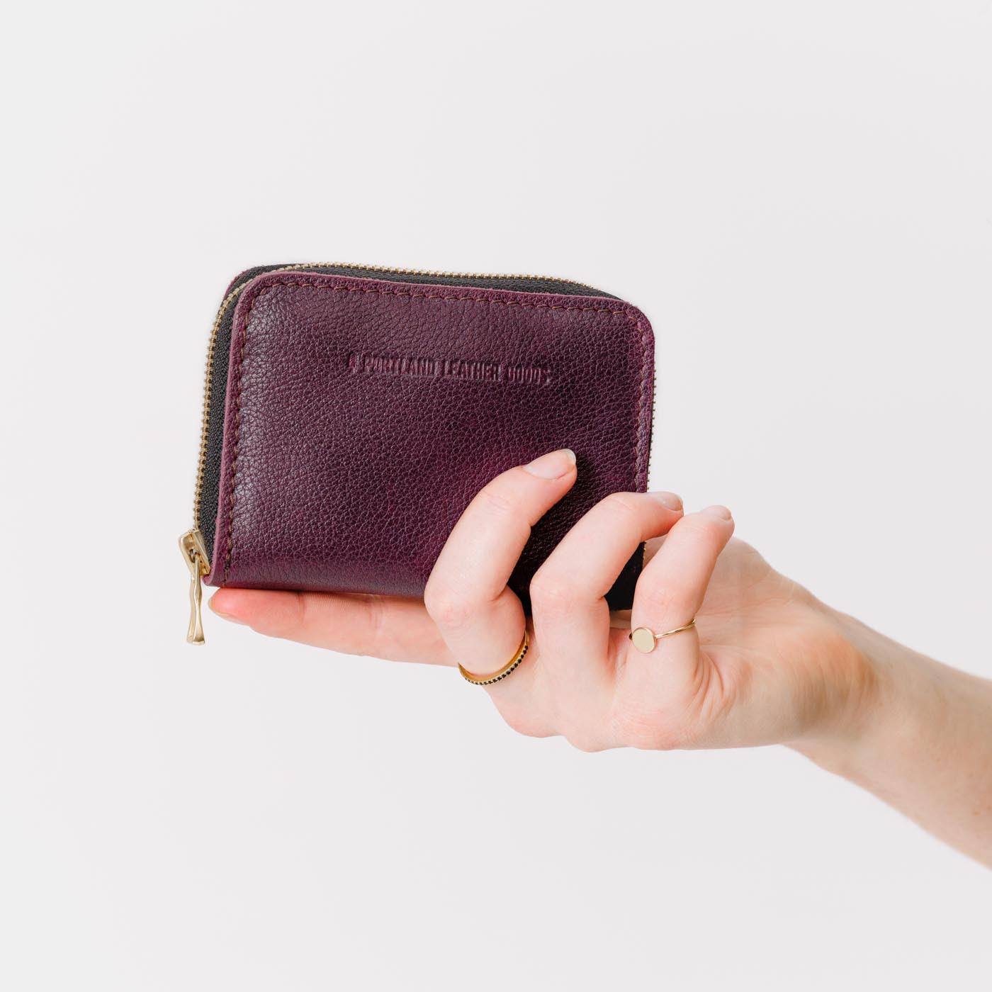 Plum | Model holding small leather wallet with zipper closed