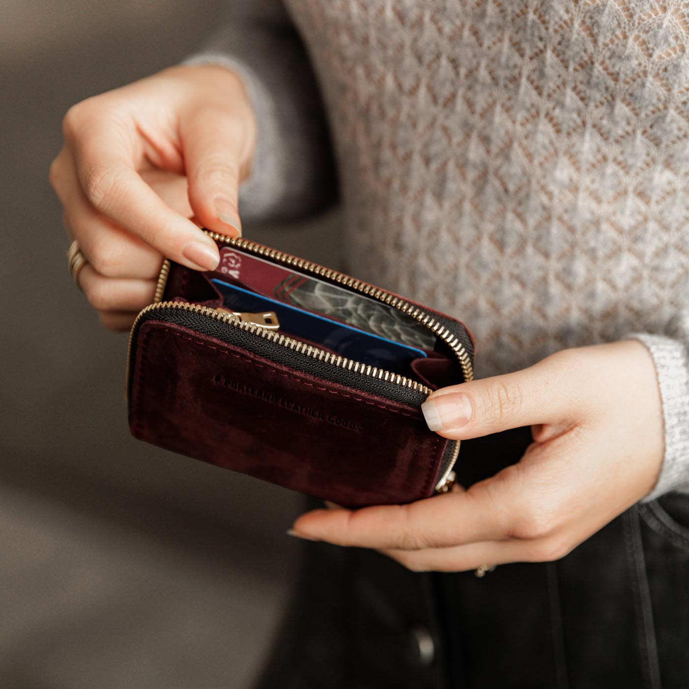 Merlot | Model holding small leather wallet with zipper open