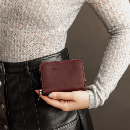 Merlot | Model holding small leather wallet with zipper closed